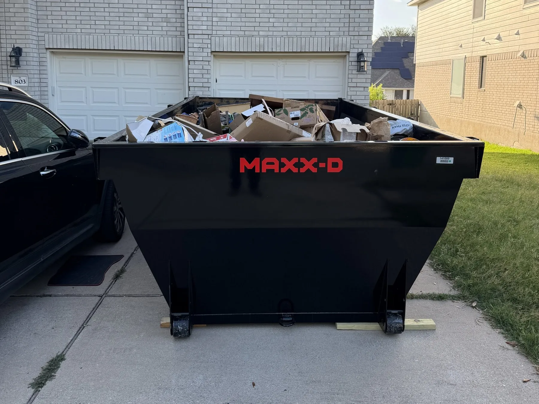 Dumpster filled with moving boxes in front of a two-story home